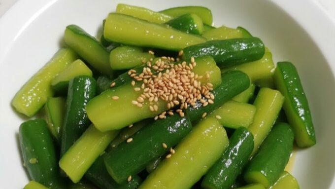 白い皿に盛り付けられた、シャキシャキとした食感が伝わるきゅうりの炒め物。ごまが散らされており、美味しそうな中華料理のイメージ。